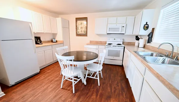 a kitchen with a refrigerator a stove a sink and white cabinets with wooden floor