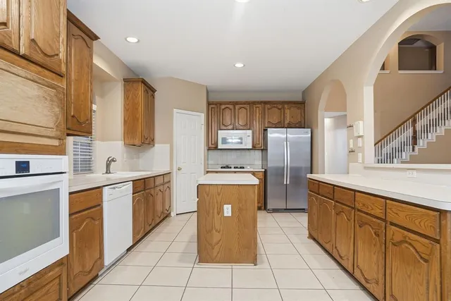 a kitchen with stainless steel appliances granite countertop a refrigerator and a stove top oven