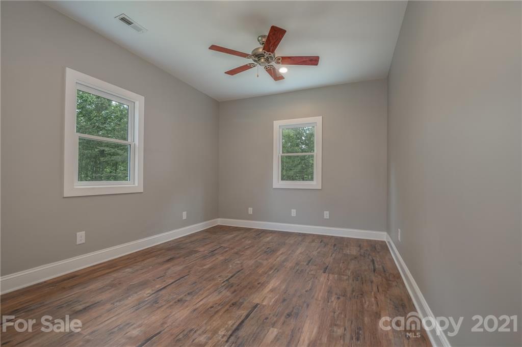 196 Caledonia Road Landrum, SC 29356 - Photo 16 of 26 an empty room with wooden floor and windows