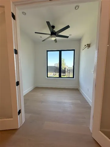 an empty room with windows and ceiling fan