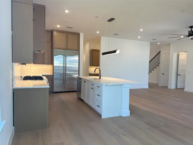 a large kitchen with stainless steel appliances a large counter top a sink and a refrigerator