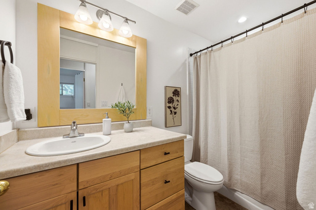 1709 Meadowmoor Road Holladay, UT 84117 - Photo 22 of 32 Bathroom featuring a light wood-finish vanity with an integrated sink, a light-toned countertop, and an overhead vanity light fixture