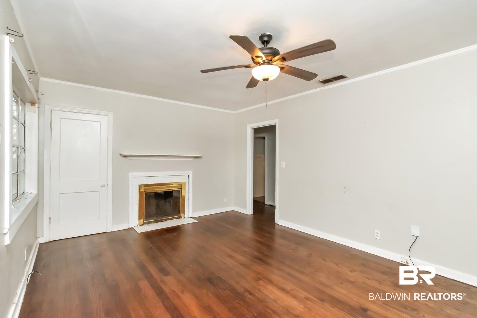 5001 Hillwood Circle South Mobile, AL 36608 - Photo 6 of 20 Unfurnished living room with visible vents, a ceiling fan, a fireplace with flush hearth, wood finished floors, and crown molding