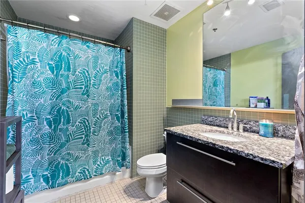 a bathroom with a granite countertop sink toilet and mirror
