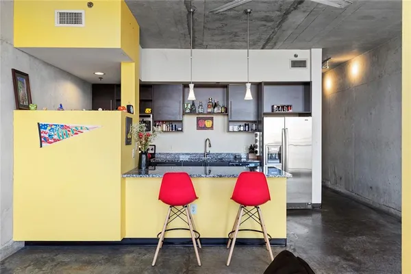 a kitchen with stainless steel appliances granite countertop a dining table chairs refrigerator and sink
