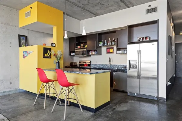 a kitchen with stainless steel appliances kitchen island granite countertop a refrigerator and microwave
