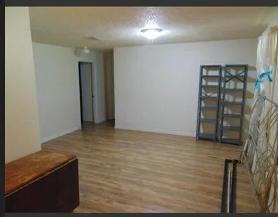 a view of an empty room with wooden floor and entryway