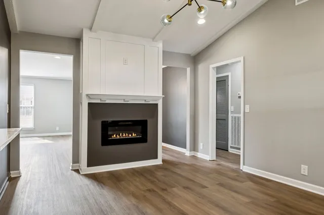 an empty room with wooden floor fireplace and windows