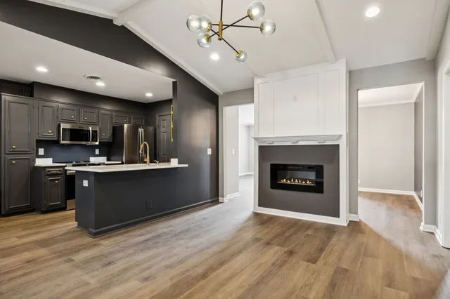 a kitchen with stainless steel appliances granite countertop a refrigerator a stove top oven and a sink with wooden floor