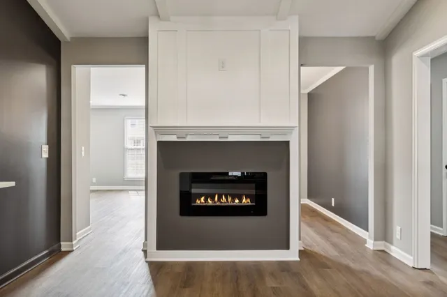 a view of an empty room with wooden floor and a fireplace