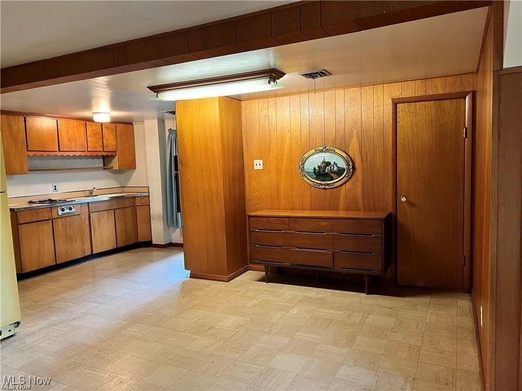 8581 Fair Road Strongsville, OH 44149 - Photo 2 of 20 Kitchen featuring light flooring, brown cabinets, light countertops, freestanding refrigerator, and wood walls