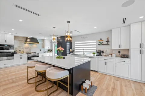 a kitchen with granite countertop a sink appliances cabinets and chair
