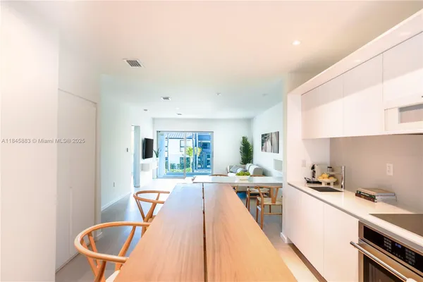 a kitchen with stainless steel appliances granite countertop a sink a stove a dining table and chairs