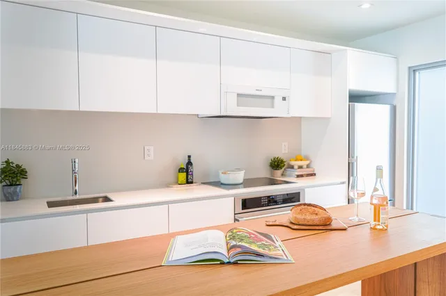 a kitchen with stainless steel appliances kitchen island granite countertop a sink a stove and white cabinets
