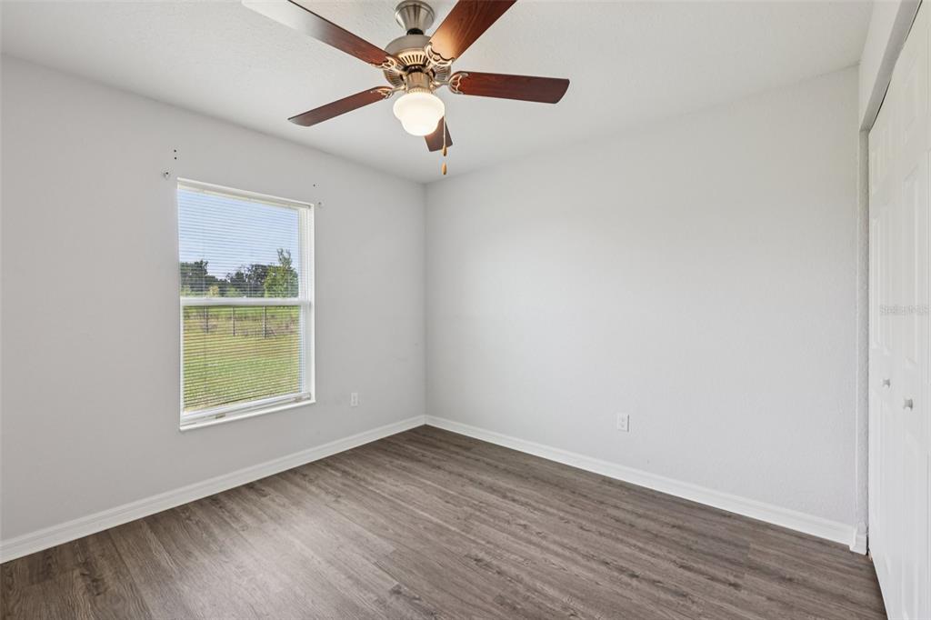 5 Laurel Pass Court Ocala, FL 34480 - Photo 18 of 23 an empty room with wooden floor chandelier fan and windows