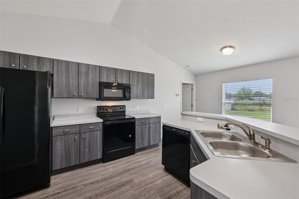 5 Laurel Pass Court Ocala, FL 34480 - Photo 9 of 23 a kitchen that has a sink a stove a refrigerator cabinets and a dining table with wooden floor