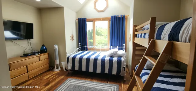 a bedroom with a bed and flat tv screen on the dresser