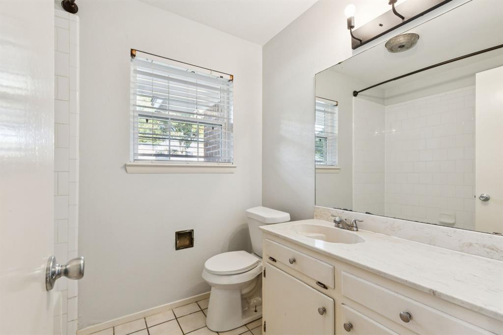 1602 England Road Arlington, TX 76013 - Photo 19 of 27 a bathroom with a toilet a sink a mirror and a shower