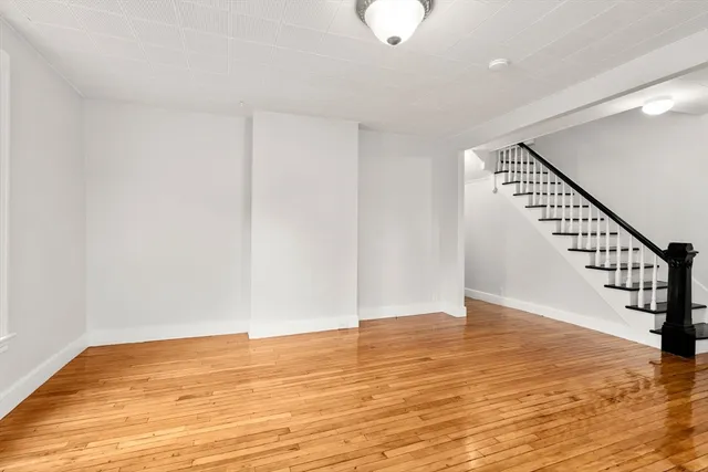 a view of an empty room with wooden floor and stairs