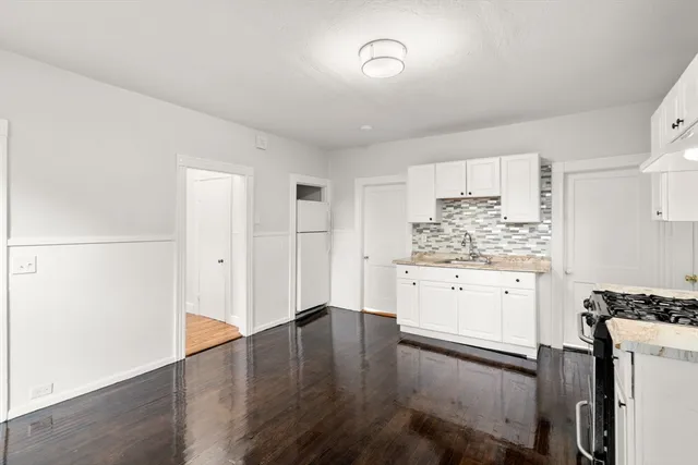 a kitchen with a refrigerator and white cabinets