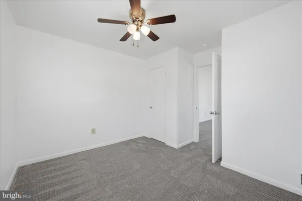an empty room with a chandelier fan and windows