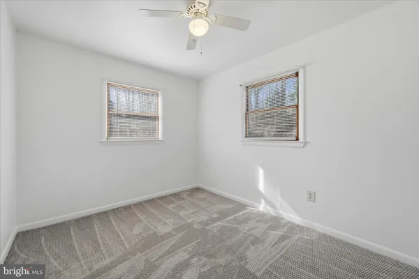an empty room with a chandelier fan and wooden floor