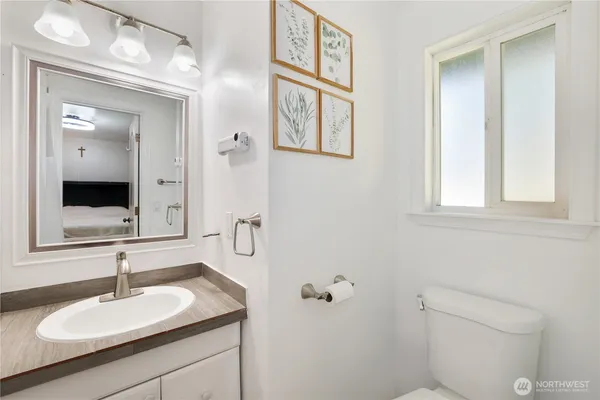 a bathroom with a granite countertop sink toilet and mirror