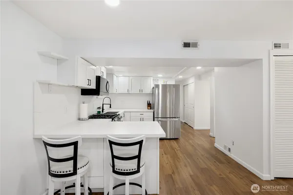 a kitchen with kitchen island a wooden floor and white cabinets