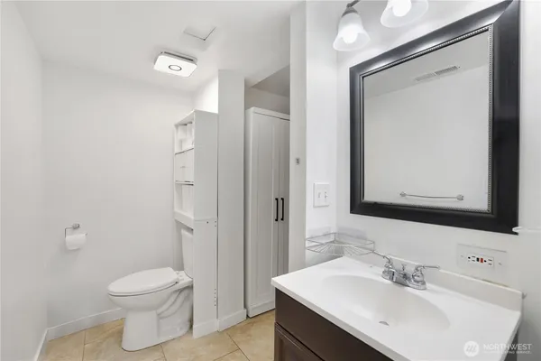 a bathroom with a toilet a sink a mirror and vanity