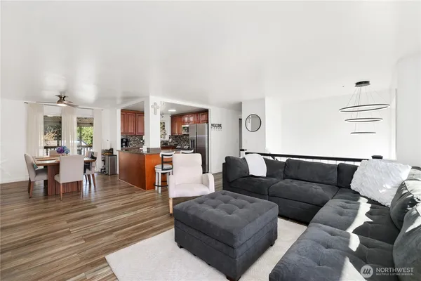a living room with furniture kitchen view and a wooden floor