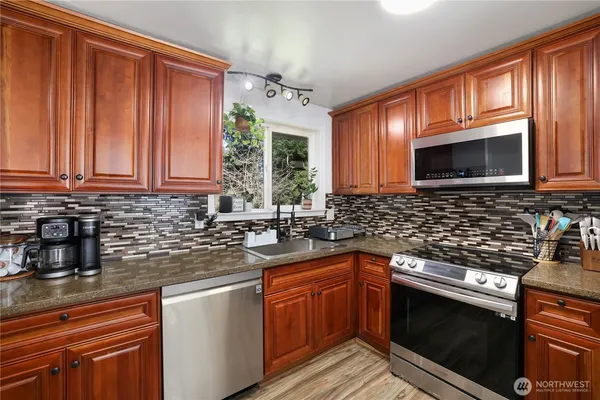 a kitchen with stainless steel appliances granite countertop a stove microwave and sink