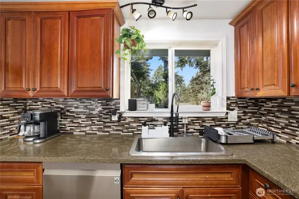 a kitchen with granite countertop a sink a window and stainless steel appliances