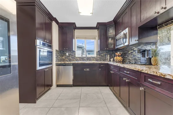 a kitchen with stainless steel appliances granite countertop a stove a sink and a refrigerator