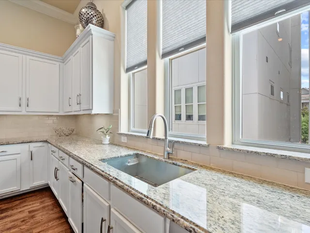 a kitchen with stainless steel appliances granite countertop a stove a sink a microwave a refrigerator and white cabinets