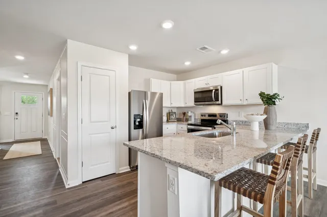 a kitchen with stainless steel appliances granite countertop a refrigerator a stove a microwave a sink and dishwasher with wooden floor