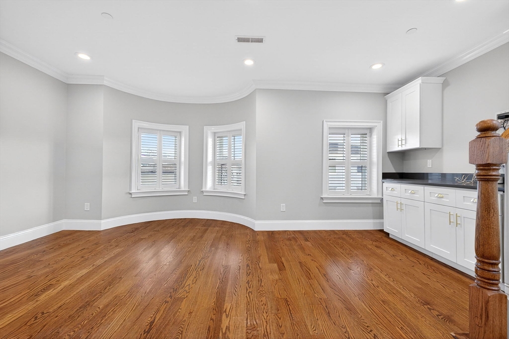 137 N Street, Unit 3 Boston, MA 02127 - Photo 11 of 28 a open kitchen with granite countertop a stove top oven a sink dishwasher and white cabinets with wooden floor