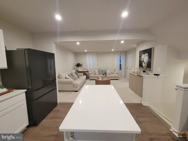 a living room with stainless steel appliances furniture a refrigerator and a counter top space