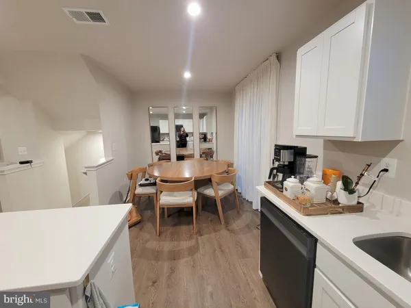 a kitchen with a dining table chairs sink and white cabinets