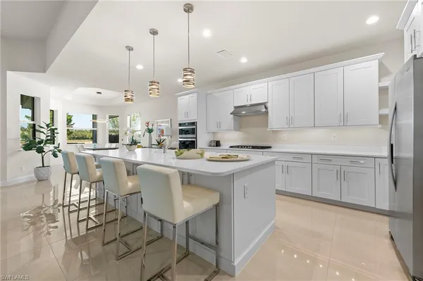 a kitchen with stainless steel appliances kitchen island a table chairs sink and cabinets