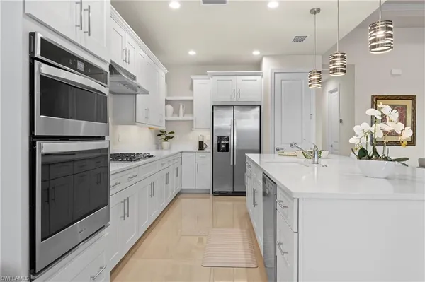 a kitchen with stainless steel appliances kitchen island granite countertop a sink and refrigerator