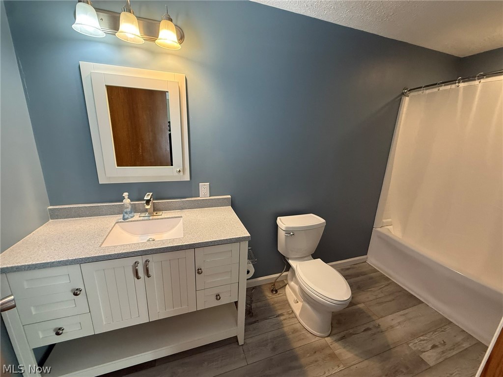 6784 Old Zoarville Road Northeast Dover, OH 44622 - Photo 22 of 50 Bathroom featuring dark wood-style flooring, vanity, shower / tub combo with curtain, and a textured ceiling