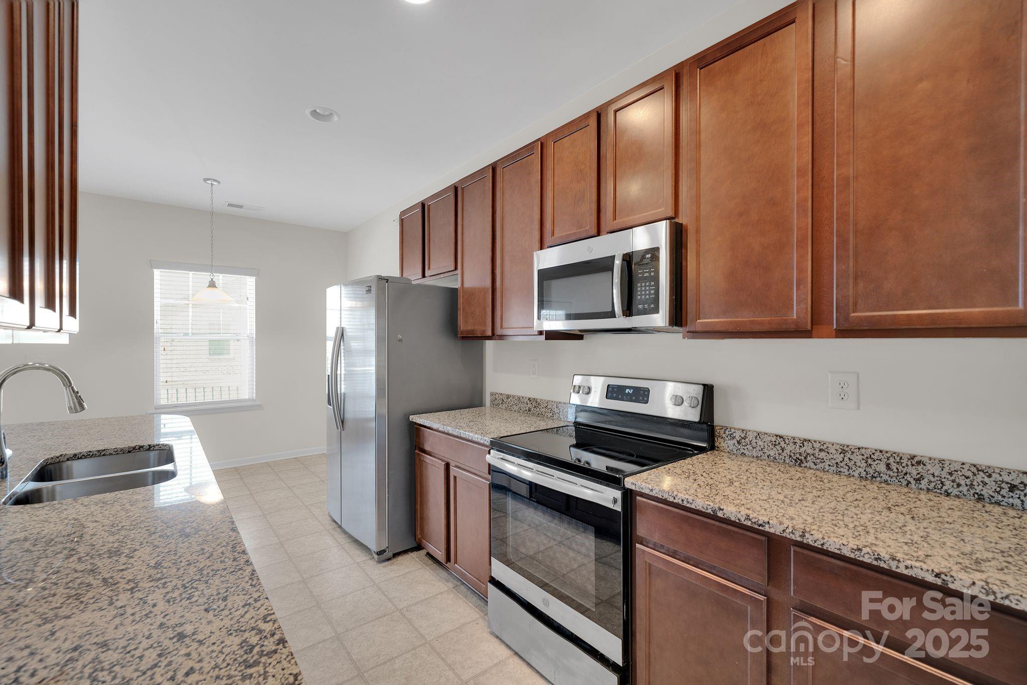6439 Prosperity Church Road Charlotte, NC 28269 - Photo 5 of 46 a kitchen with stainless steel appliances granite countertop a sink stove and microwave