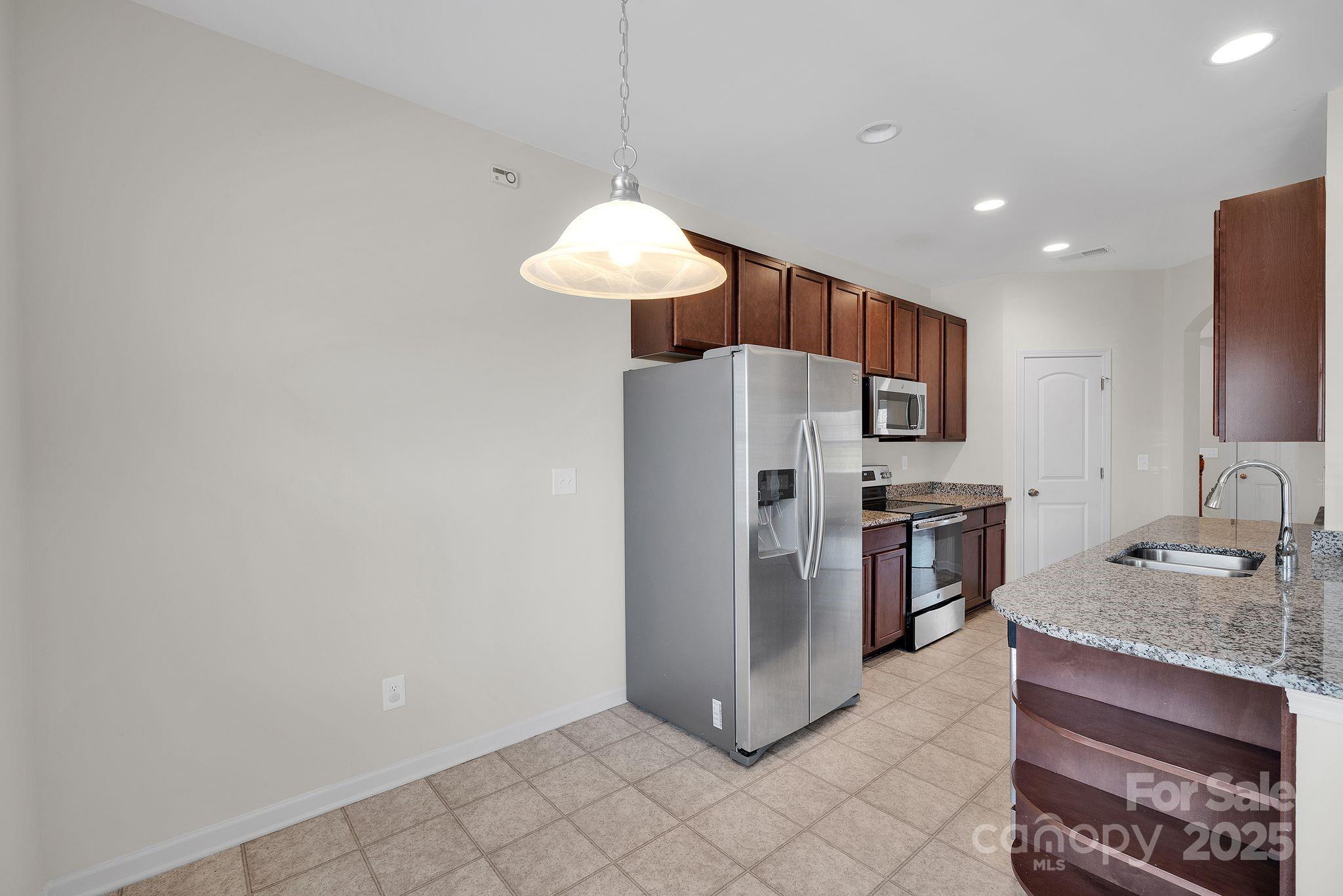 6439 Prosperity Church Road Charlotte, NC 28269 - Photo 9 of 46 a kitchen with stainless steel appliances granite countertop a refrigerator and a sink