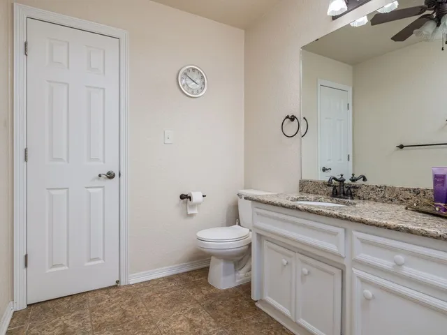 a bathroom with a granite countertop toilet a sink and a mirror