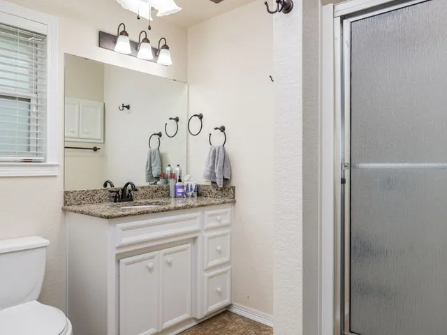 a bathroom with a granite countertop sink a toilet and a mirror