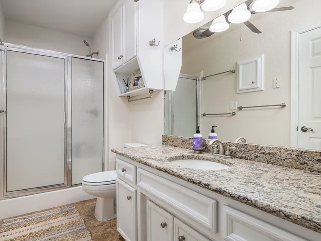 a bathroom with a granite countertop sink a toilet and a shower