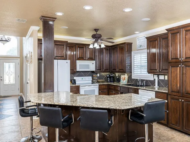 a kitchen with stainless steel appliances kitchen island granite countertop a table chairs in it and wooden floors