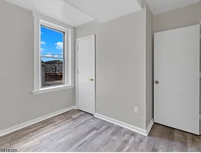 84 Second Street, Unit 4 Elizabeth Port, NJ 07206 - Photo 4 of 16 a view of an empty room with window and wooden floor