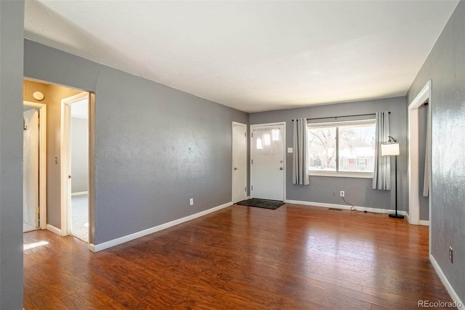 3016 South Grape Way Denver, CO 80222 - Photo 2 of 27 an empty room with wooden floor and windows
