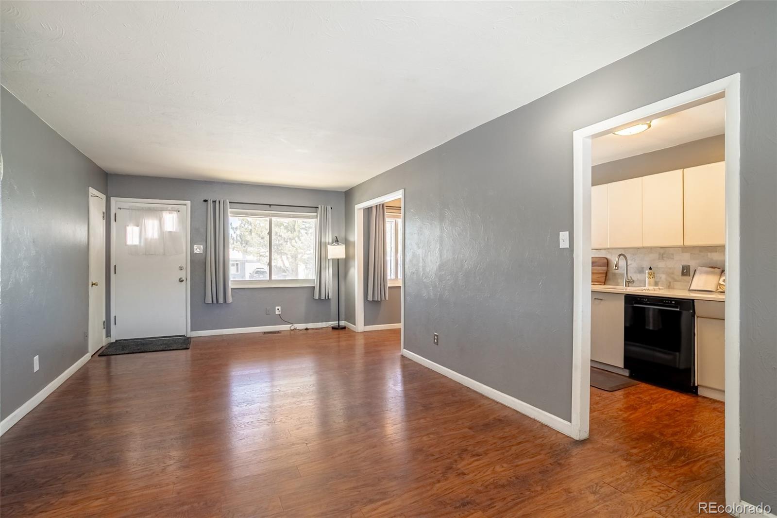 3016 South Grape Way Denver, CO 80222 - Photo 3 of 27 an empty room with windows and kitchen view